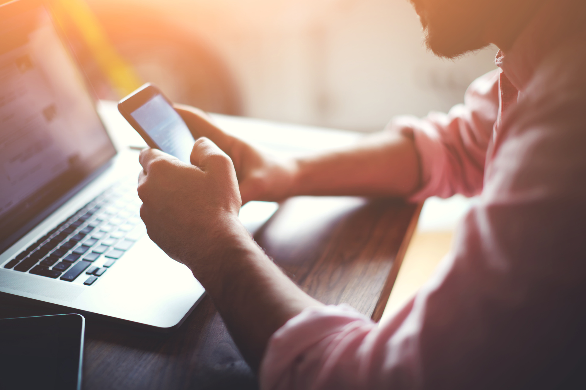 Man working from home using smart phone and notebook computer